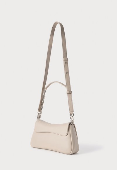 Μπεζ δερμάτινη τσάντα ώμου με κυρτό σχήμα, επίπεδη μπροστινή όψη, ρυθμιζόμενο μακρύ λουρί και ασημένια αλυσίδα διακοσμητικό στοιχείο προσαρτημένο.
