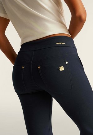 Leggings stretch bleu marine avec une taille haute, comportant des détails en métal doré, des poches arrière et un détail de marque subtil à la taille.