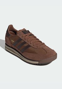 Brown Adidas SL 72 sneaker with suede and fabric upper, three black stripes, textured tongue, and rubber sole.