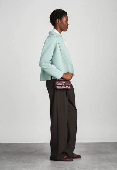 Light teal wool jacket, white shirt, dark wide-leg trousers, burgundy quilted handbag with chain strap, and matching loafers.