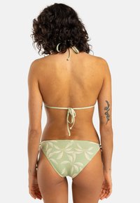 Grön bikini med knytbaksdesign. Har ett lövmönster på trosorna, mjuk tygkvalitet och justerbara sidoknytningar.