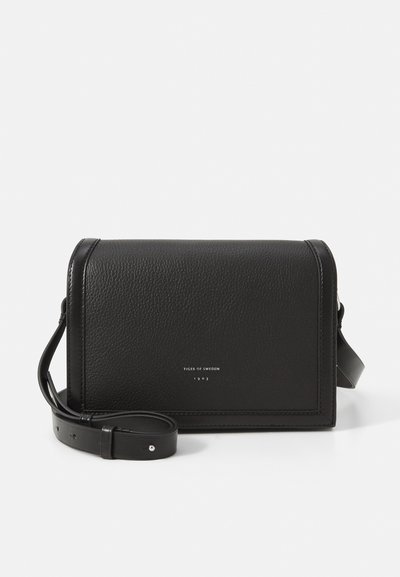 Bolso cruzado de cuero negro con superficie texturizada, forma estructurada y correa ajustable. Presenta un logo en relieve en la parte frontal.