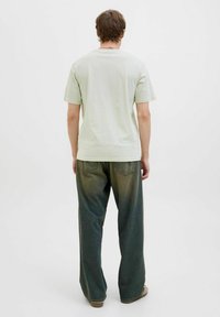 Lys grøn bomulds t-shirt kombineret med løstsiddende mørkegrønne jeans med en falmet gradient. Enkel design, korte ærmer, diskret syninger.