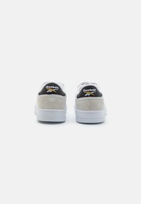 Sneaker bianche con accenti neri e grigi, sezioni in camoscio, cuciture a contrasto e suola in gomma. Presentano un logo sul tallone.