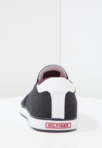 Marinblå kanvassko med vit hälkappa, rosa inredning och vit gummisula. Röd "HILFIGER" logotyp på baksidan. Enkel, låg profil design.