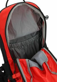 Interno dello zaino rosso e nero con foderatura grigia, tasca elastica e zipper bidirezionale per accesso e organizzazione.