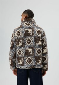 Sfeervol geruit jasje in bruine, crèmekleurige en blauwe tinten, met een hoge kraag en lange mouwen, afgewerkt met een textuurrijk, zacht pluche.