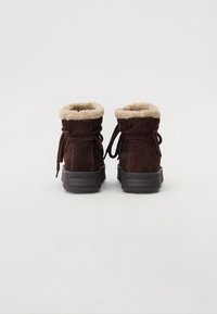 Bottines en daim marron avec doublure en fausse fourrure, bout rond, design à lacets et semelle en caoutchouc texturé. Présente un logo embossé à l'arrière.