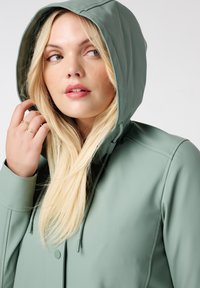 Lichtgroene waterdichte jas met een capuchon, met een gladde textuur en verstelbare koordjes. Bevat knoopdetails en een slank ontwerp.