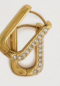 Zlaté klipsové náušnice s průhlednými kulatými krystaly uspořádanými ve dvou řadách podél vnějších okrajů na bílém pozadí.