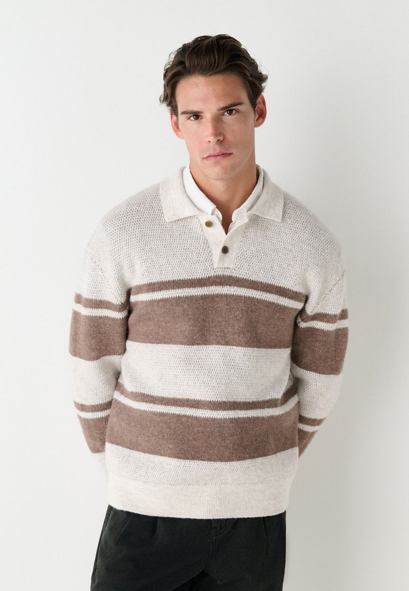 Knit sweater in cream and brown stripes, featuring a collared neckline with two button accents and a textured finish. Relaxed fit.