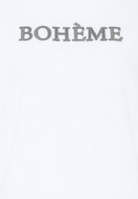 Tissu blanc avec texte brodé en gris « BOHÈME » centré près du haut.