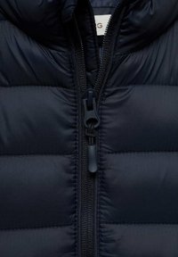 Granatowa kurtka puchowa z pikowanym wzorem, z zamkiem błyskawicznym z przodu i uchwytem, oraz kapturem. Gładki, lekki materiał o miękkiej fakturze.