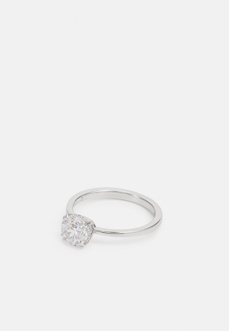 Bague en argent avec une pierre ronde et transparente entourée de petites accentuations, d'un bandeau lisse et poli, avec un design de sertissage classique.