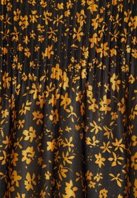 Schwarzer Stoff mit einem floralen Muster in Senfgelb. Faltentextur mit verschiedenen Blumenformen und -größen im gesamten Design.