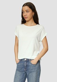 Weißes Kurzarm-T-Shirt mit blauen horizontalen Streifen, einem runden Ausschnitt und umgeschlagenen Ärmeln, kombiniert mit hellblauen Denim-Jeans.