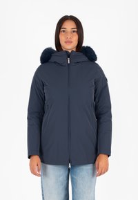 Giacca trapuntata blu navy con bordo in pelliccia sintetica, chiusura con zip, fodera accogliente e tasche laterali; progettata per calore e comfort.