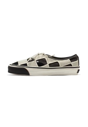 Zapatilla baja con parte superior de malla a cuadros en blanco y negro, cordones blancos y suela blanca gruesa con panel negro en la puntera.