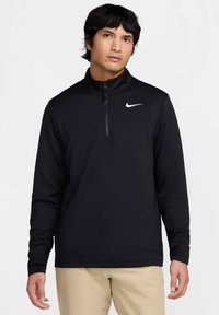 Svart Nike-pullover med halv-zip krage, lange ermer, og en hvit logo på venstre bryst. Mykt stoff med en glatt tekstur.