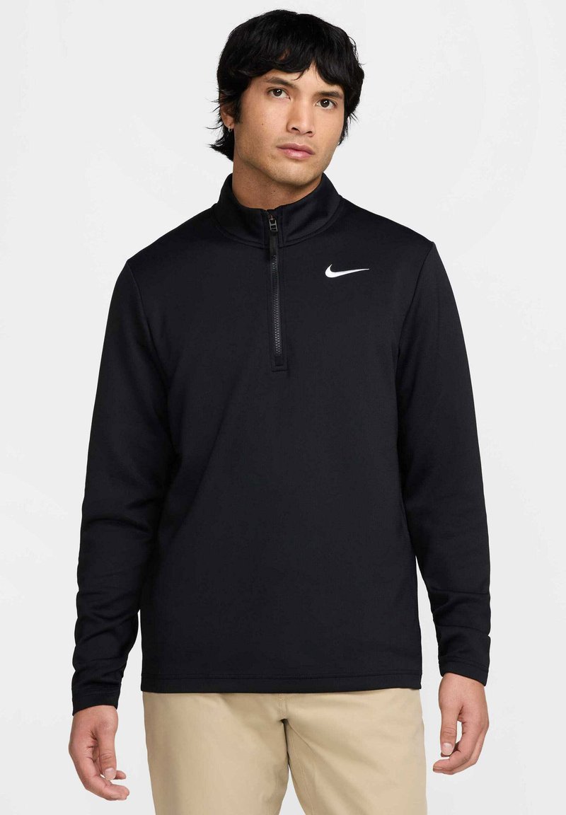 Svart Nike-pullover med halv-zip krage, lange ermer, og en hvit logo på venstre bryst. Mykt stoff med en glatt tekstur.