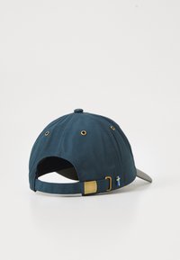 Marineblå baseballcap med en buet skygge, stoftekstur, messing hardware og et lille svensk flag-dekoration nær den justerbare rem.