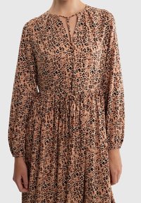 Robe en imprimé léopard avec un décolleté en trou de serrure, de longues manches ballons, une taille froncée et un tissu doux et léger dans des nuances de beige et de brun.