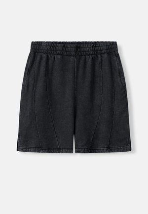 Svarte shorts laget av mykt, teksturert stoff. Har elastisk midjebånd, sidelommer og vertikale sømmer som gir form.