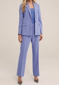 Ljuslila kostym bestående av en figursydd kavaj och vida byxor, tillverkad i ett mjukt tyg; har framfickor och en enkel knapp.