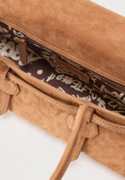 Sac à main en daim couleur camel avec fermeture éclair visible sur le dessus, longues bandoulières et doublure intérieure en tissu imprimé noir et blanc.