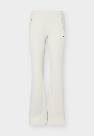 Εκρού παντελόνι με φαρδιά γραμμή, δύο μπροστινές τσέπες με φερμουάρ και μικρό μαύρο λογότυπο στο δεξί μηρό, σε ουδέτερο φόντο.