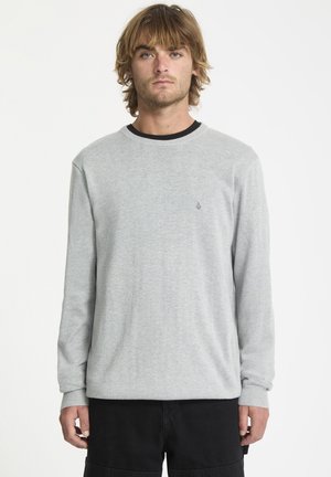 Lys grå langærmet crewneck sweater med ribstrikkede manchetter og en sort halsudskæring. Lille logo på brystet, blød tekstur og afslappet pasform.