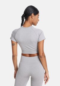 Szary zestaw składający się z crop topu i legginsów o wysokim stanie, o gładkiej teksturze; ma krótkie rękawy i dopasowany krój.