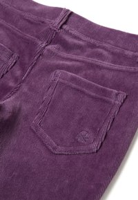 Fialové kordové kalhoty s zadní kapsou s jemným prošíváním a embosovaným logem, které zdůrazňuje texturu a barvu látky.