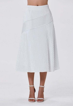 Jupe midi blanche avec de fines rayures grises verticales et diagonales, portée avec des talons blancs à bride cheville, visible de la taille aux pieds.