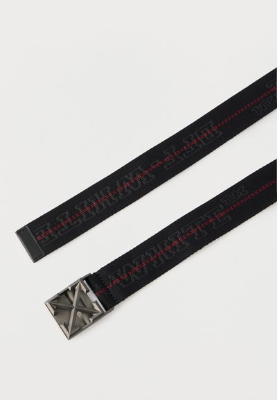 Μαύρη υφασμάτινη ζώνη με κόκκινη ραφή που διατρέχει το κέντρο και τετράγωνη μεταλλική αγκράφα με ανάγλυφο γεωμετρικό αστέρι.