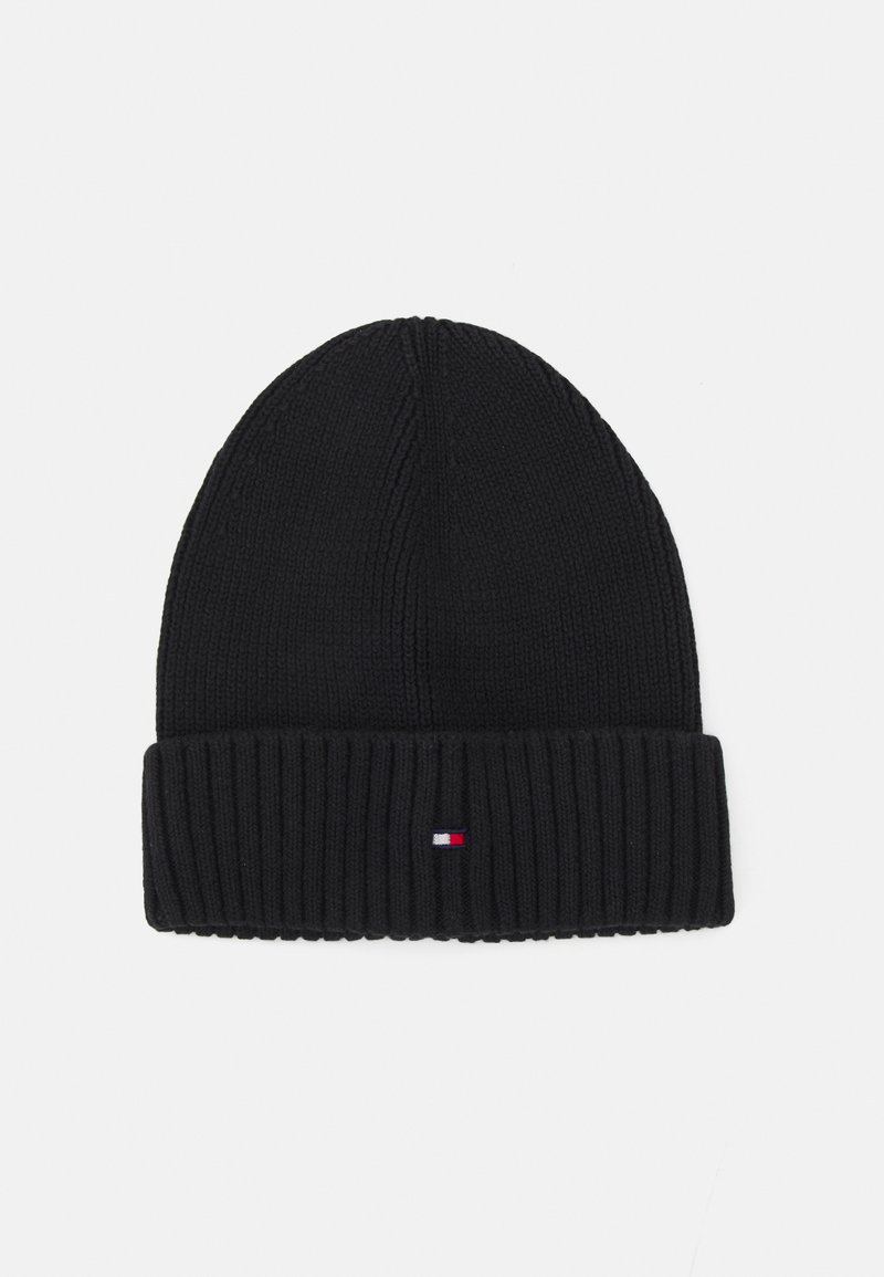 Black knitted beanie with a ribbed cuff. Features a small logo tag with red, white, and blue accents on the cuff. Soft, textured material.