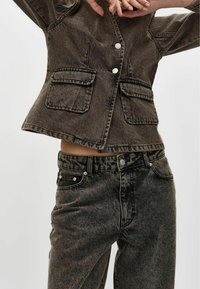 Halli denimpluus, millel on kaks eesmist taskut, hõbedased nööbid ja lühendatud disain, koos sobivate hallide denimhapendustega, millel on klassikaline viie tasku stiil.