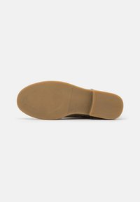 Suela de zapato marrón hecha de caucho con un acabado liso y texturizado. Presenta un tacón redondeado y ligeramente elevado, sin patrones visibles.