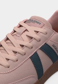 Ροζ σουέντ αθλητικό παπούτσι με ανοιχτό ροζ κορδόνια, σκούρες μπλε λωρίδες στο πλάι και σήμανση «Jack & Jones» στη γλώσσα και στο πλαϊνό πάνελ.