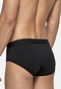Black men's briefs with a solid texture, featuring a wide elastic waistband embossed with "IMPETUS." Close-fitting, mid-rise design.