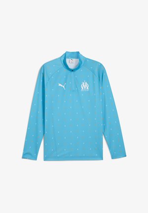 Jasnoniebieski długi rękaw pulower z zamkiem na szyi, w kropkowany wzór w kolorze żółtym i białym, z logo Pumy i emblematem drużyny na klatce piersiowej.