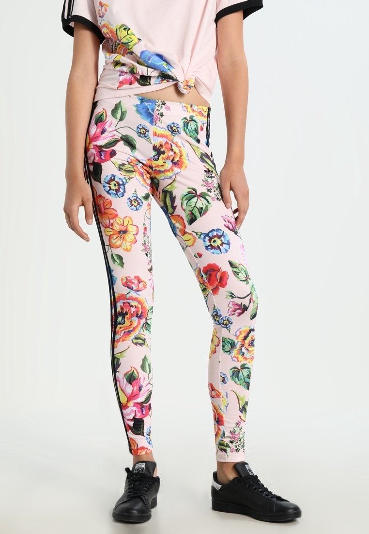 Blommiga leggings med en ljusrosa bas, prydda med färgglada blommönster, sidostickningar och en figurnära design. Svarta sneakers fulländar looken.