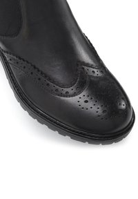 Zwarte leren schoen met brogue-detaillering, textiele bovenkant, elastische inzet voor een goede pasvorm en een duurzame rubberen zool.