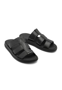 Czarne skórzane sandały o grubym, paskowym wzorze. Posiadają otwarty czubek i płaską gumową podeszwę, zapewniającą teksturową powierzchnię.