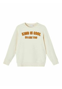 Cream-colored sweatshirt made of soft fabric, featuring raglan sleeves, rounded neck, and orange fuzzy text saying "KIND IS COOL SO ARE YOU."
