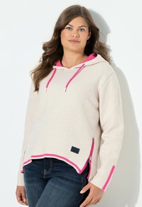 Hoodie beige clair avec une capuche et des poignets accentués de rose. Il présente un ourlet arrondi, des zips sur les côtés et un petit logo près du bas.