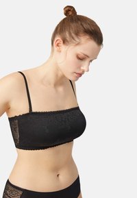 Bralette de encaje negro con tirantes finos ajustables, patrón floral, borde con ondas y acabado suave. Combinado con braguitas negras.
