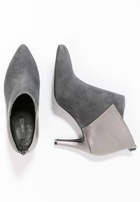 Stivaletti alla caviglia in suede grigio con tacco metallico argento, punta appuntita e pannello posteriore argento a contrasto. Chiusura con zip sul tallone.