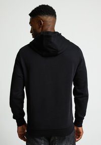 Sudadera con capucha negra de manga larga, hecha de una tela suave. Presenta puños y dobladillo acanalados, y un diseño de corte relajado.