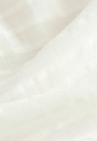 Biały, lekki materiał o miękkiej fakturze, z delikatnymi poziomymi paskami. Materiał wydaje się przezroczysty i przewiewny, z cienkim splotem.